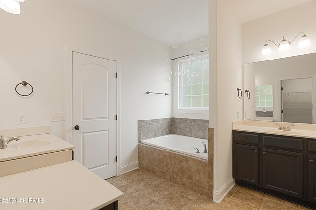 bathroom featuring tiled bath, vanity, and tile patterned floors