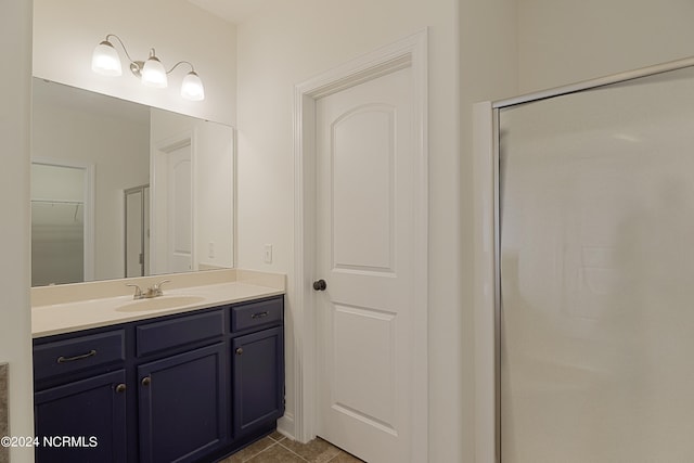 bathroom with tile patterned flooring, an enclosed shower, and vanity