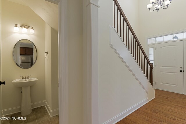 foyer entrance featuring hardwood / wood-style flooring, vaulted ceiling, and a chandelier