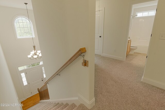 carpeted entryway featuring an inviting chandelier and a healthy amount of sunlight