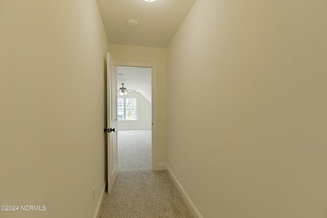 hall featuring carpet flooring and vaulted ceiling