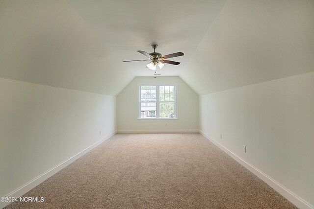 additional living space with ceiling fan, vaulted ceiling, and light colored carpet