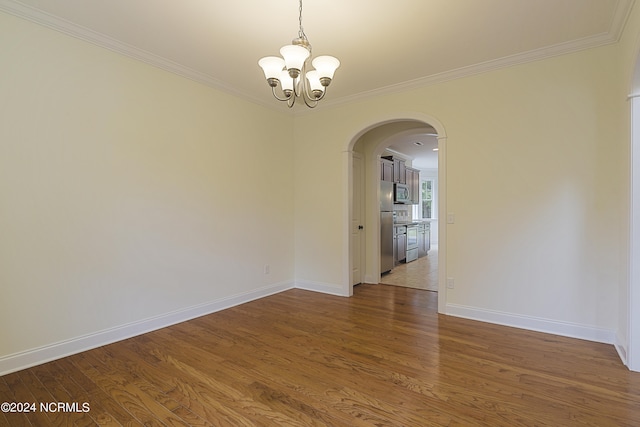 unfurnished room with hardwood / wood-style floors, crown molding, and a notable chandelier