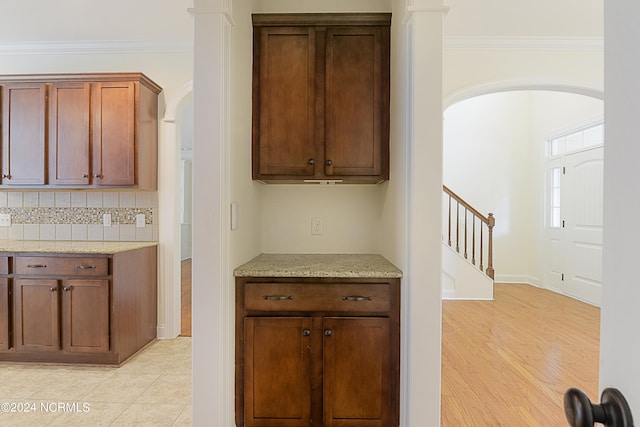 kitchen featuring light hardwood / wood-style flooring, light stone countertops, ornamental molding, and tasteful backsplash