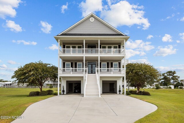 view of front of property featuring a balcony, a front yard, and a garage