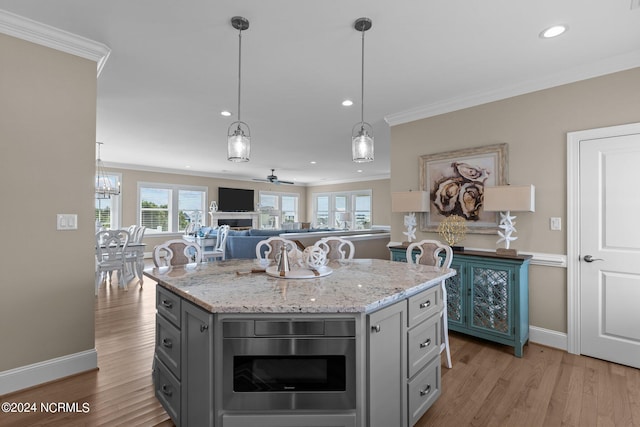 kitchen with light hardwood / wood-style flooring, a center island, light stone countertops, and ornamental molding