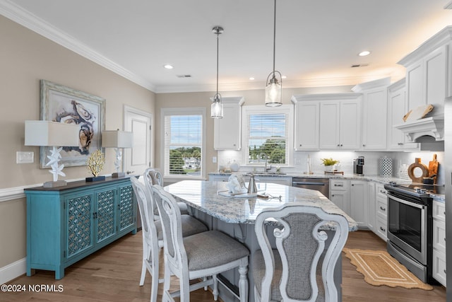 kitchen featuring hardwood / wood-style floors, appliances with stainless steel finishes, light stone countertops, and a kitchen island