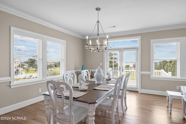 dining room with light wood-type flooring, an inviting chandelier, and ornamental molding