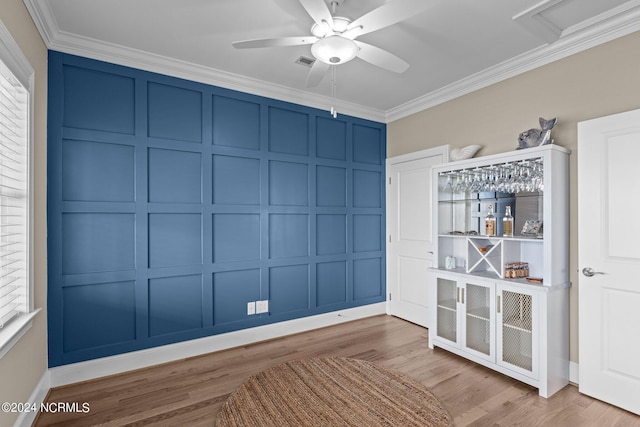 interior space with ornamental molding, wood finished floors, and a decorative wall