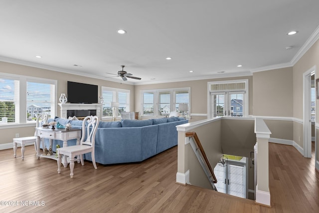 living room with baseboards, ornamental molding, wood finished floors, a fireplace, and recessed lighting