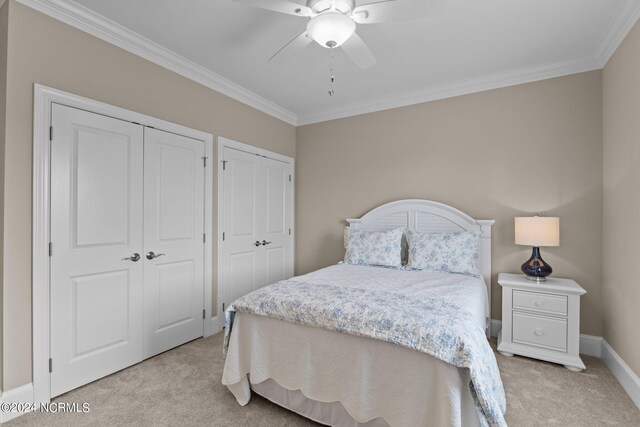 carpeted bedroom with ceiling fan, multiple closets, and ornamental molding