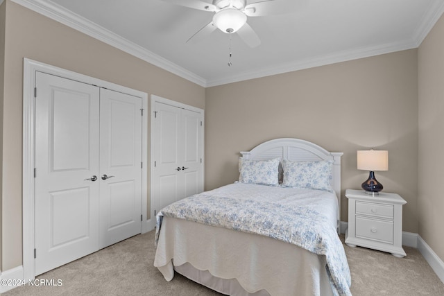 bedroom featuring baseboards, a ceiling fan, light colored carpet, crown molding, and multiple closets