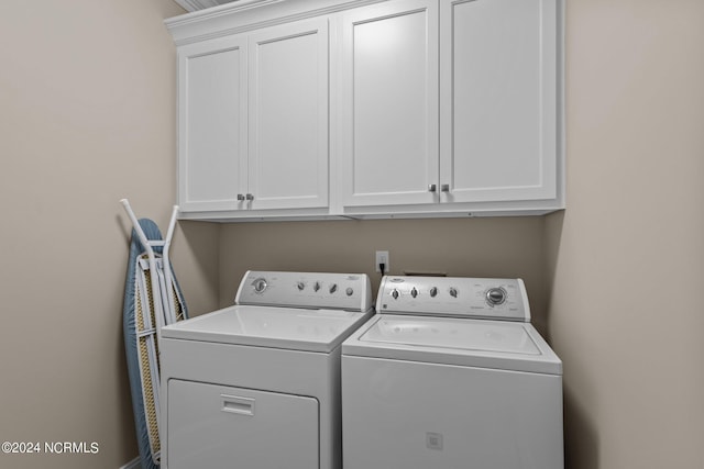 clothes washing area featuring separate washer and dryer and cabinet space