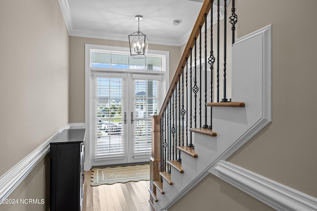 entryway featuring hardwood / wood-style flooring, french doors, crown molding, and a chandelier