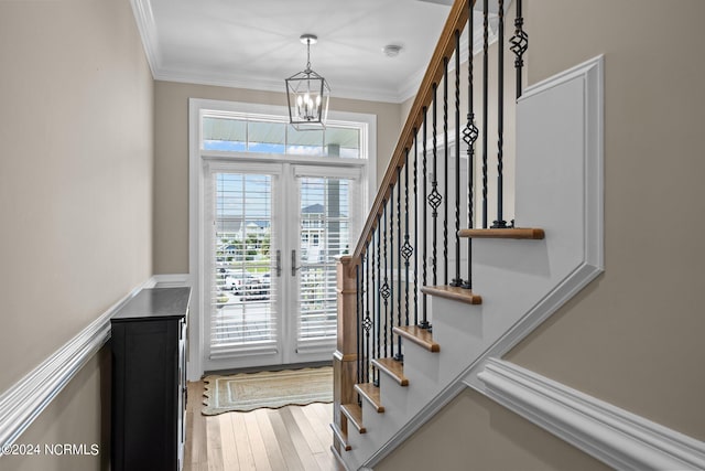 foyer featuring stairway, wood finished floors, crown molding, french doors, and a chandelier