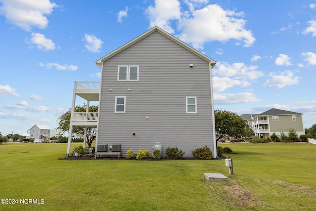 rear view of property featuring a yard, central AC unit, and a balcony