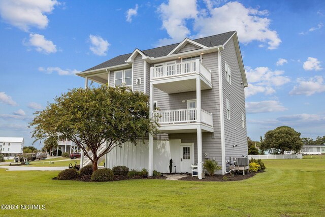 view of front of house featuring cooling unit, a balcony, and a front lawn