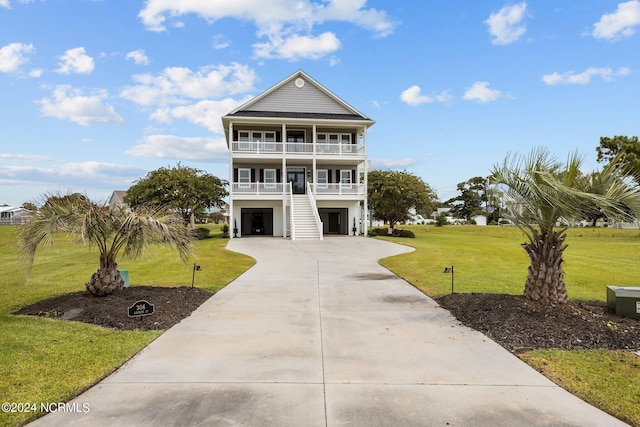 coastal home featuring a garage, concrete driveway, a balcony, and a front lawn