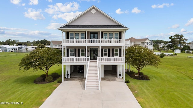 coastal inspired home with a carport, a front yard, covered porch, and driveway