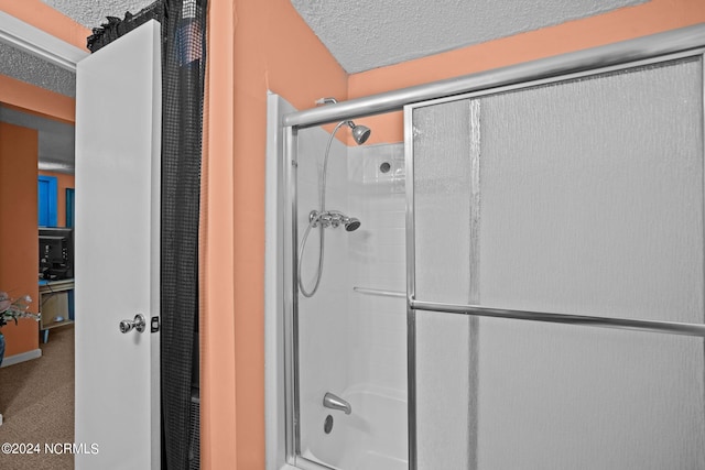 bathroom with a textured ceiling and a shower with door