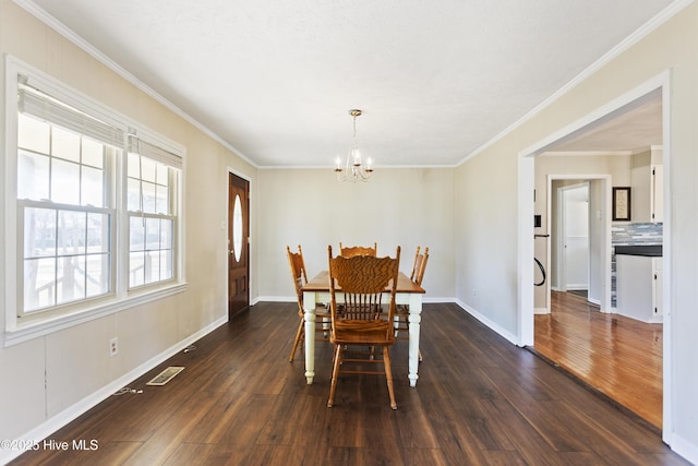 dining space with crown molding, dark wood-type flooring, and a chandelier