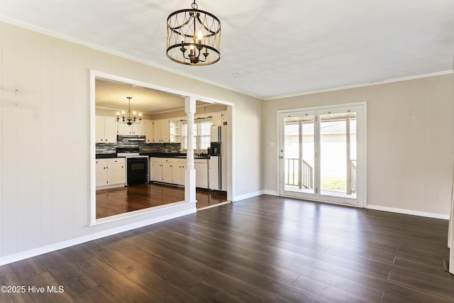 unfurnished living room featuring dark wood-type flooring, an inviting chandelier, and ornamental molding