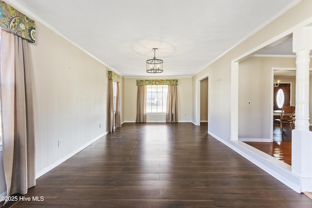 unfurnished room featuring ornate columns, dark hardwood / wood-style flooring, ornamental molding, and a notable chandelier
