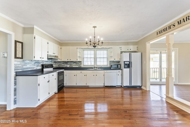 kitchen with pendant lighting, white appliances, white cabinets, hardwood / wood-style flooring, and a chandelier