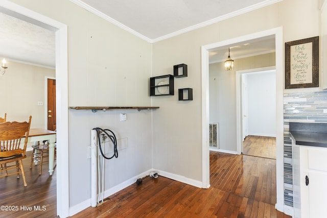 clothes washing area with a notable chandelier, dark hardwood / wood-style floors, ornamental molding, and a textured ceiling