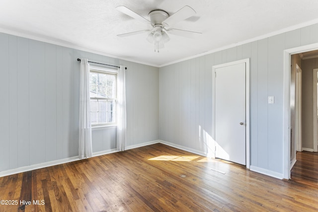 empty room with dark hardwood / wood-style flooring, ceiling fan, and ornamental molding