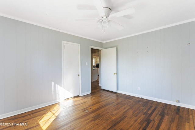 spare room with crown molding, ceiling fan, dark wood-type flooring, and wood walls