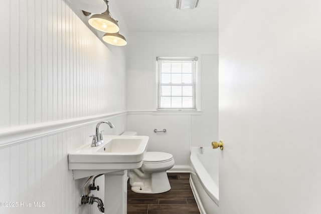 bathroom featuring a bath, toilet, and ornamental molding