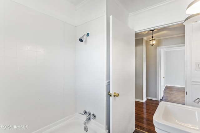 bathroom with a tub to relax in, hardwood / wood-style flooring, sink, and ornamental molding