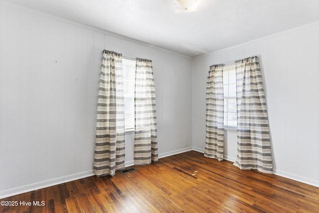 empty room featuring dark hardwood / wood-style floors, plenty of natural light, and wood walls