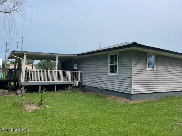 back of house with a deck and a lawn