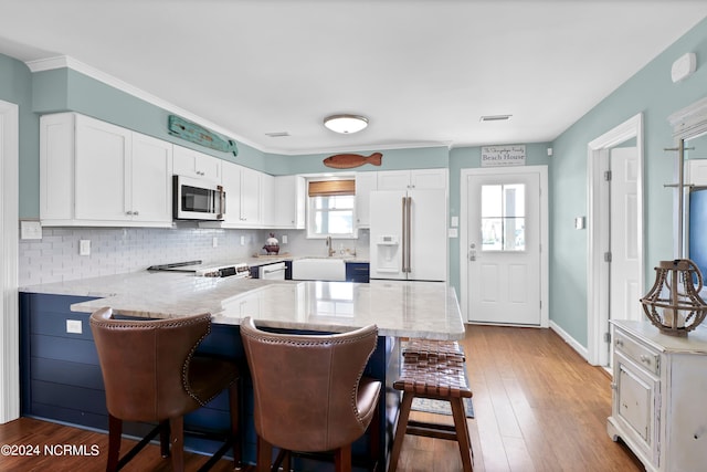 kitchen featuring a kitchen breakfast bar, kitchen peninsula, white cabinets, and appliances with stainless steel finishes