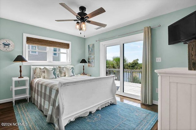 bedroom featuring access to outside, multiple windows, baseboards, and wood finished floors