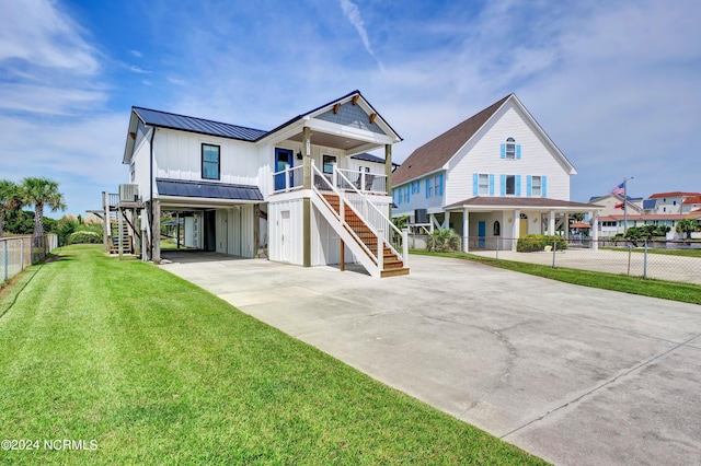 coastal inspired home with stairway, board and batten siding, a standing seam roof, driveway, and a front lawn