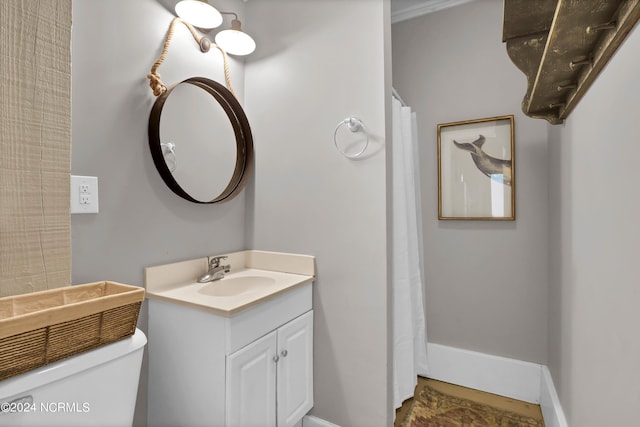 bathroom featuring toilet, baseboards, and vanity