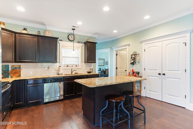 kitchen featuring hanging light fixtures, appliances with stainless steel finishes, dark hardwood / wood-style floors, a center island, and light stone countertops