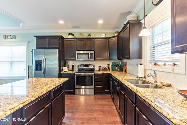 kitchen with decorative light fixtures, appliances with stainless steel finishes, crown molding, and sink