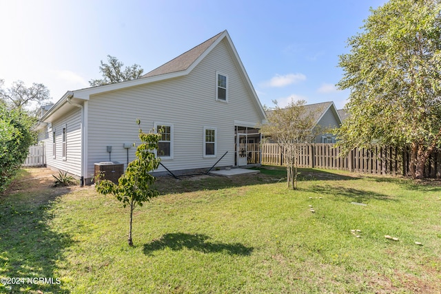 rear view of house featuring a lawn, central AC unit, and a patio area