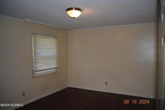 spare room with dark wood-style floors, ornamental molding, and a textured ceiling