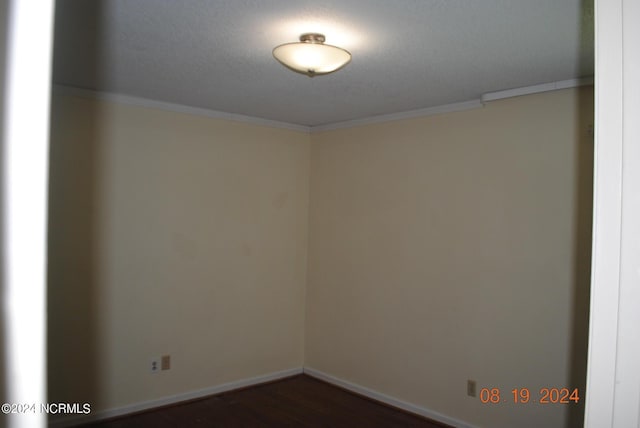 unfurnished room with baseboards, ornamental molding, and dark wood-type flooring