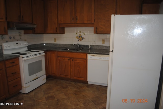 kitchen with decorative backsplash, dark stone counters, sink, dark tile patterned flooring, and white appliances