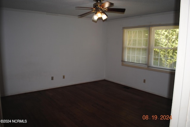 empty room with ceiling fan, ornamental molding, dark wood-style flooring, and baseboards