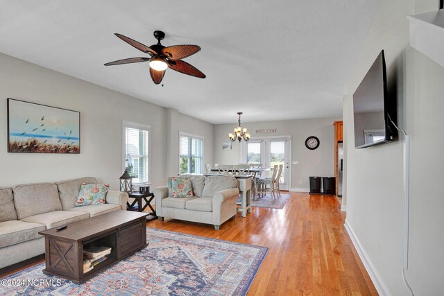 living room featuring light wood-style floors, baseboards, and ceiling fan with notable chandelier