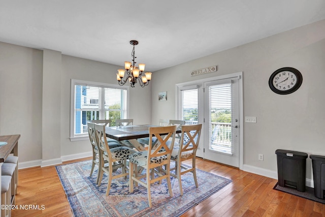 dining area with light wood-style floors, a healthy amount of sunlight, baseboards, and an inviting chandelier