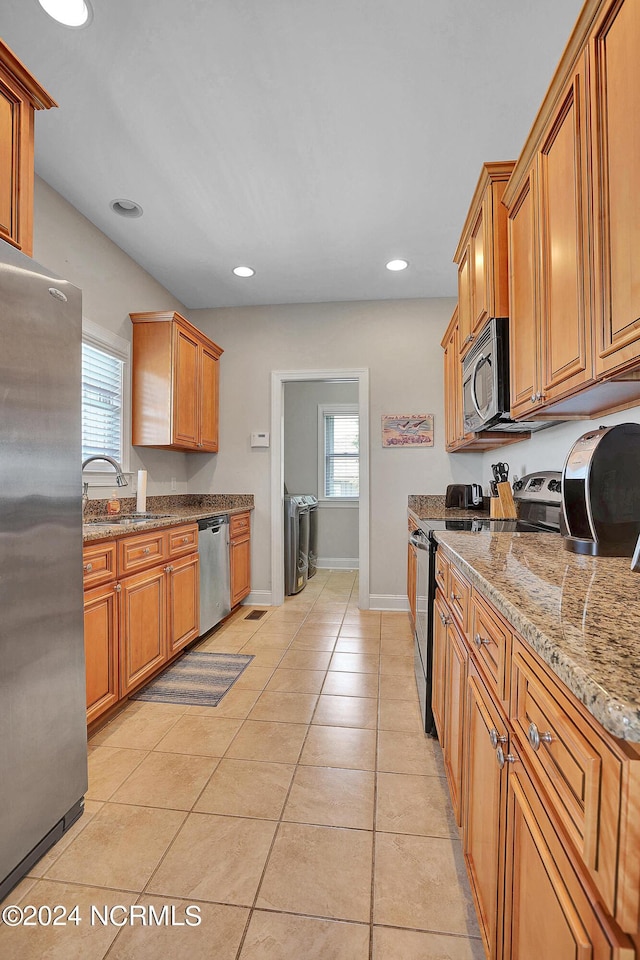 kitchen with light tile patterned floors, appliances with stainless steel finishes, a sink, and brown cabinets