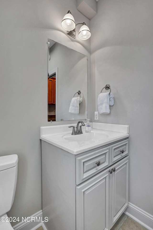 bathroom with toilet, baseboards, and vanity